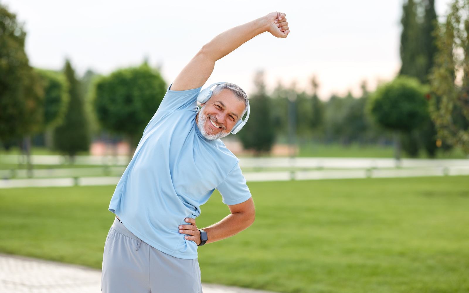 A man stretching outdoors in a park.